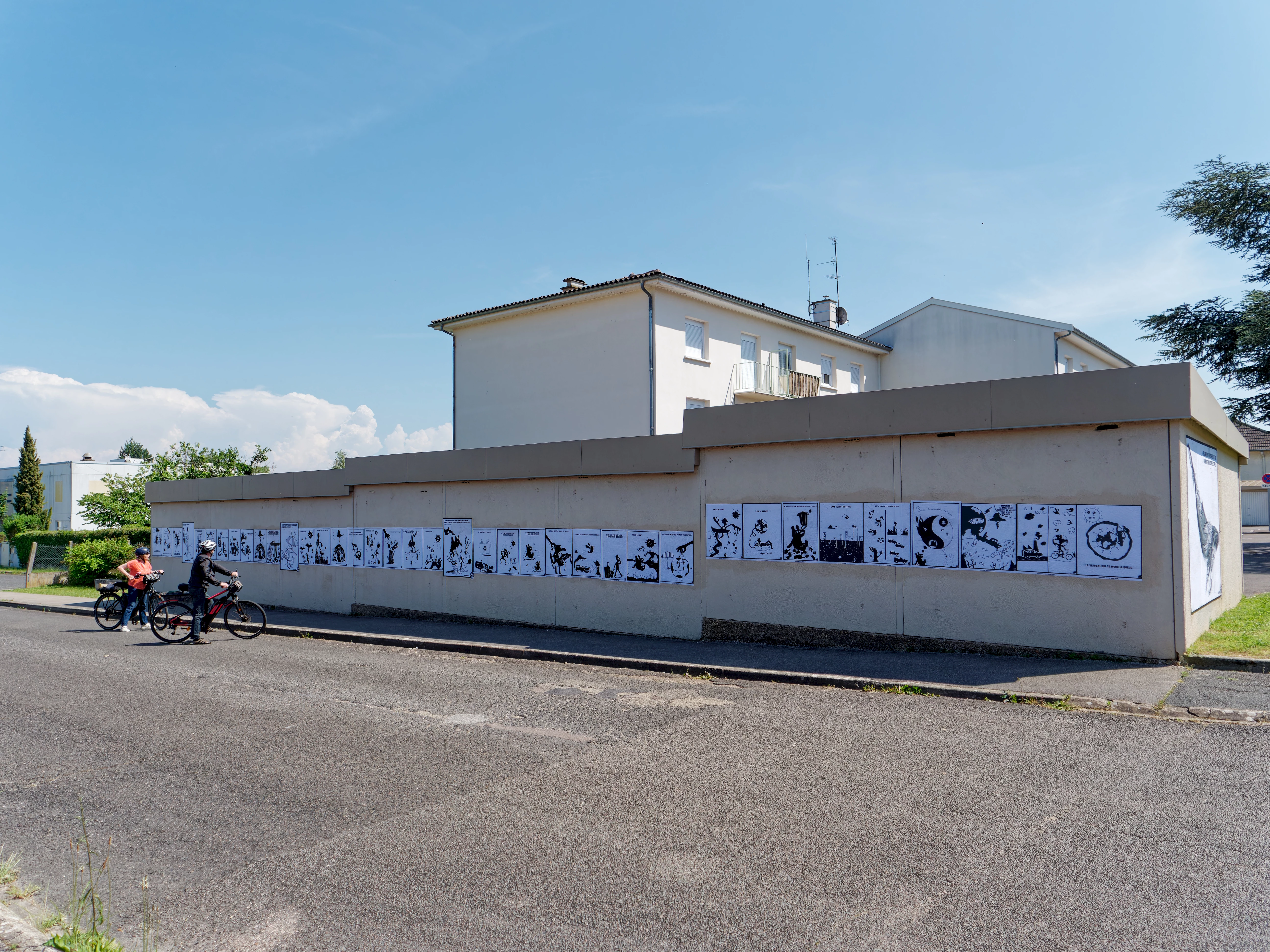Affiches coll&eacute;es sur mur avec cyclistes devant